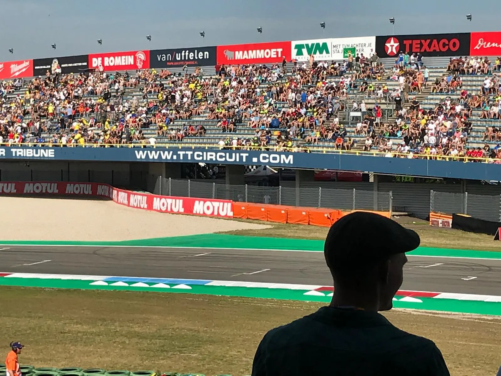 Foto van het TT Assen circuit. Uitkijkend op de racebaan met publiek op de tribune