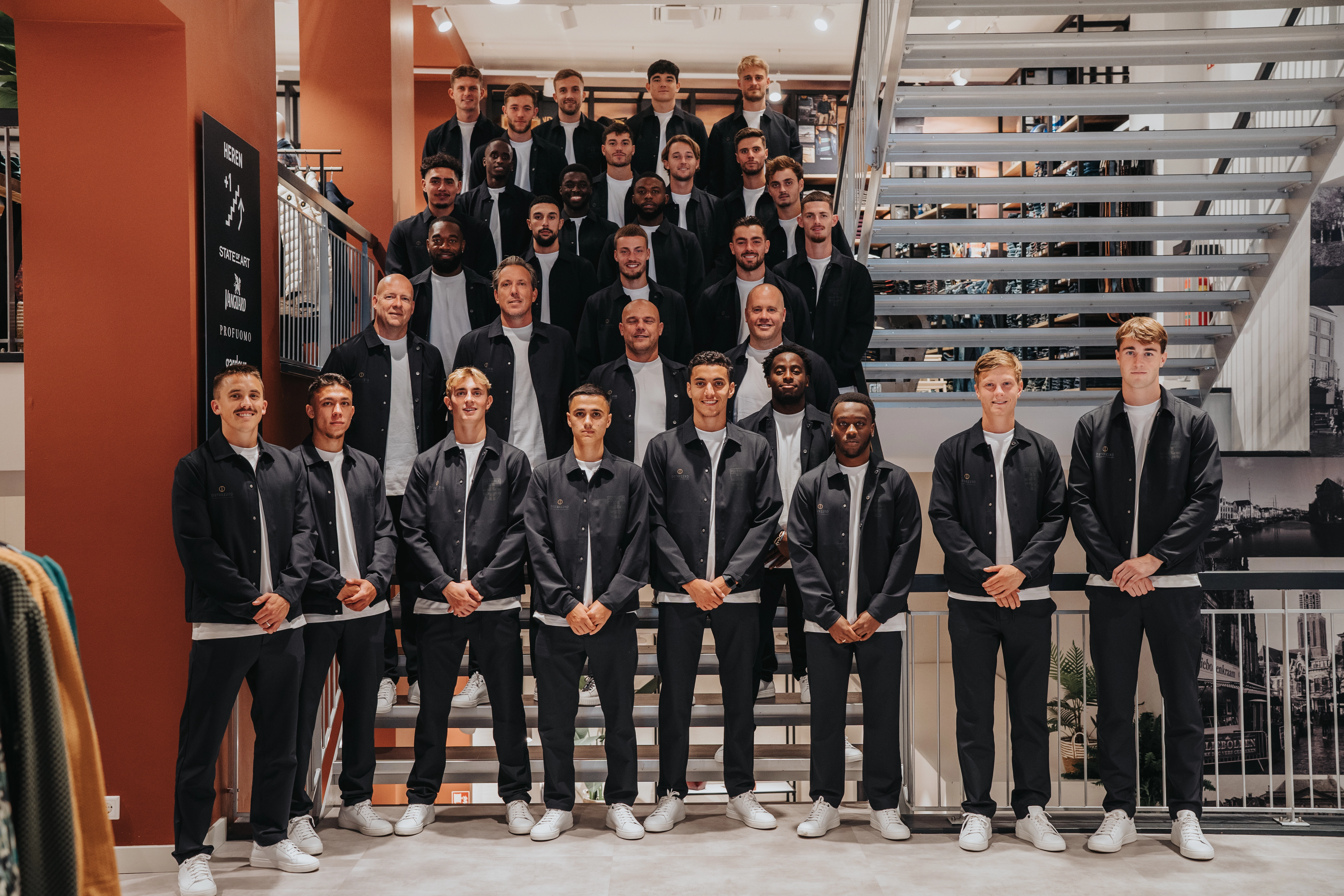 Teamfoto van het voetbalteam PEC Zwolle, poserend in een Van Uffelen winkel met een outfit van het merk Dstrezzed