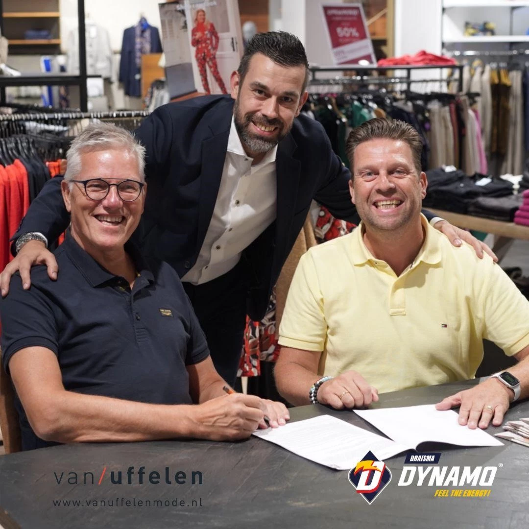 Leden van Draisma Dynamo volleybal team poserend met contract met medewerker van Van Uffelen Mode